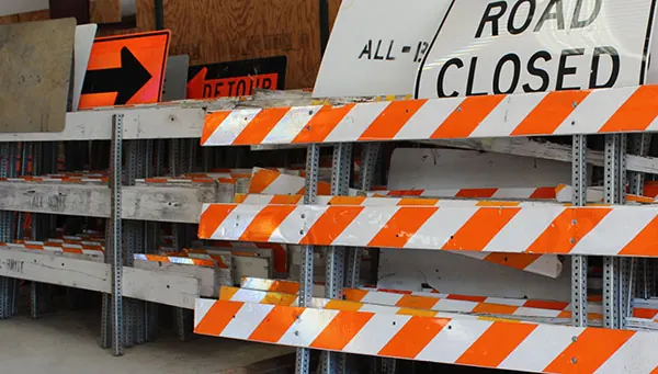 Barricades with ROAD CLOSED and DETOUR signs stacked at the All-Brite yard