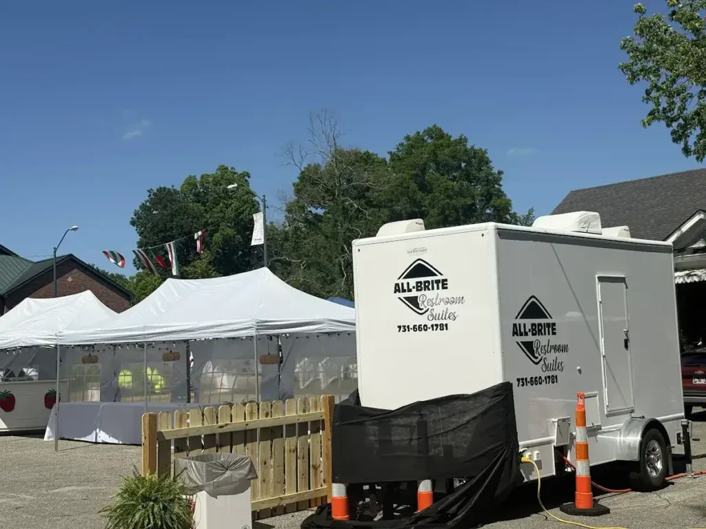 Restroom trailer beside event tents at a festival