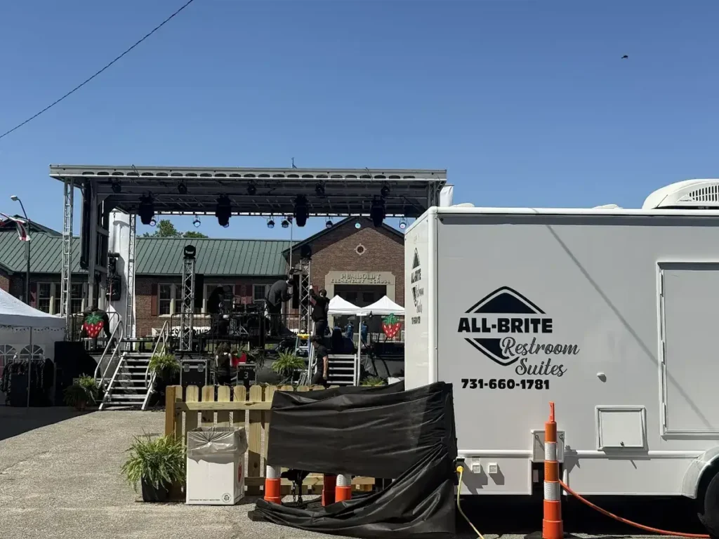 Restroom trailer under a canopy at an outdoor venue