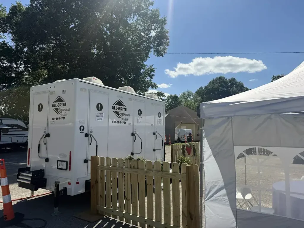 Climate-controlled restroom trailer with picket fencing at a private event
