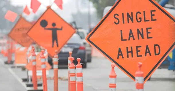 Channelizing drums and construction warning signs routing traffic through a work zone